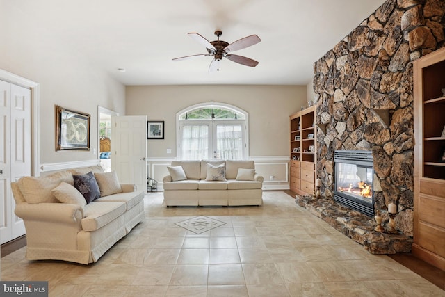 tiled living room featuring ceiling fan, french doors, and a fireplace