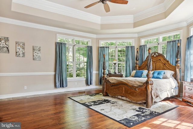 bedroom featuring ceiling fan, a raised ceiling, crown molding, and hardwood / wood-style flooring