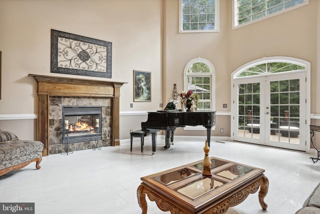 tiled living room with a towering ceiling, french doors, and a fireplace