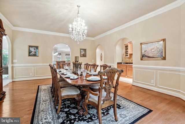 dining area featuring light hardwood / wood-style floors, ornamental molding, and a notable chandelier