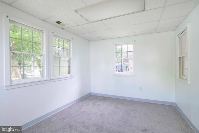 empty room featuring a wealth of natural light and a drop ceiling