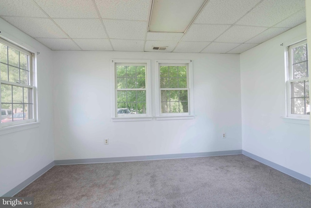 carpeted empty room with a paneled ceiling