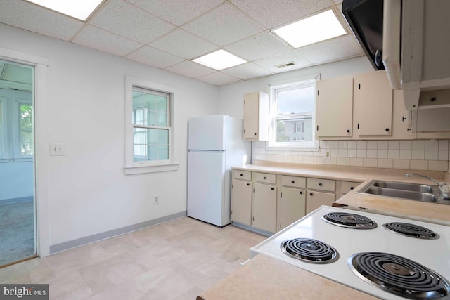 kitchen featuring white refrigerator, backsplash, a drop ceiling, sink, and light tile floors