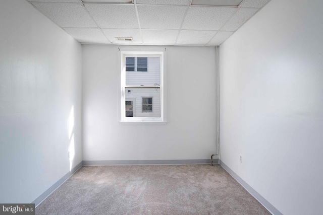 carpeted empty room with a drop ceiling