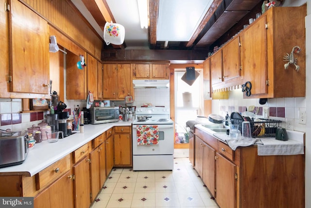 kitchen with electric range, sink, light tile flooring, and tasteful backsplash