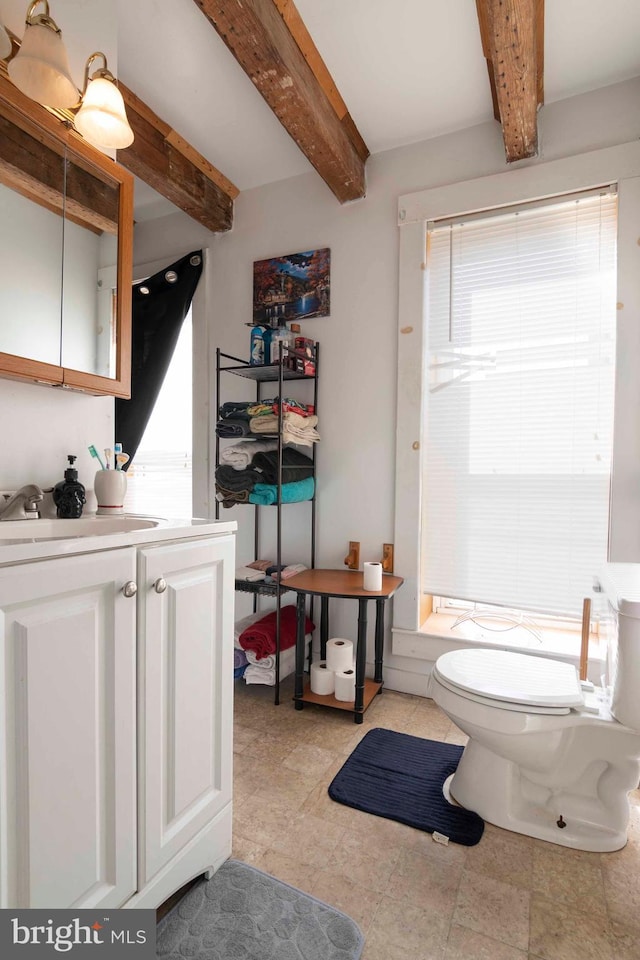 bathroom featuring beam ceiling, tile flooring, vanity, and toilet