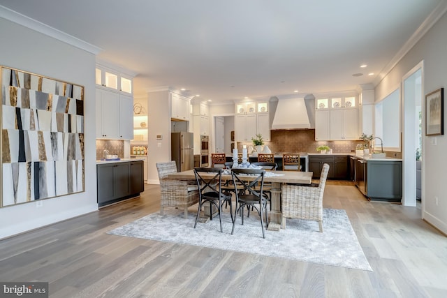 dining space featuring crown molding, sink, and light hardwood / wood-style flooring