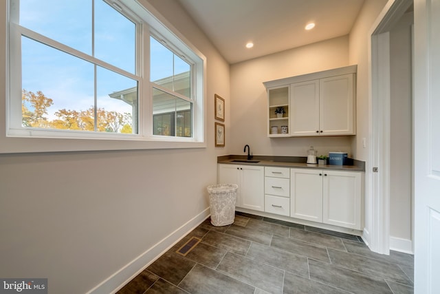 interior space featuring white cabinetry, tile flooring, and sink