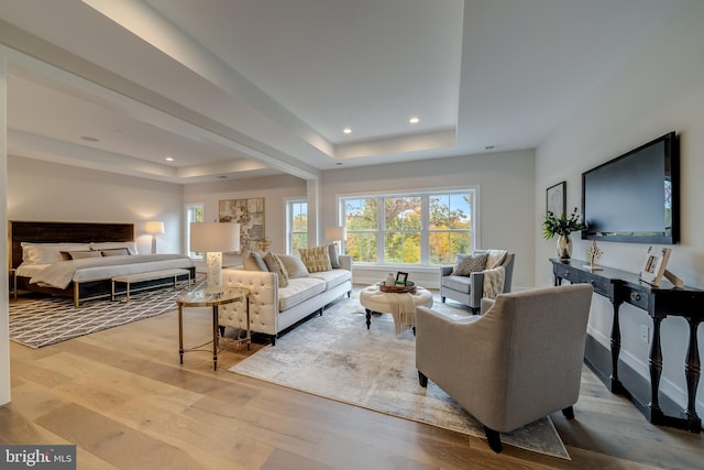 living room with a tray ceiling and light wood-type flooring