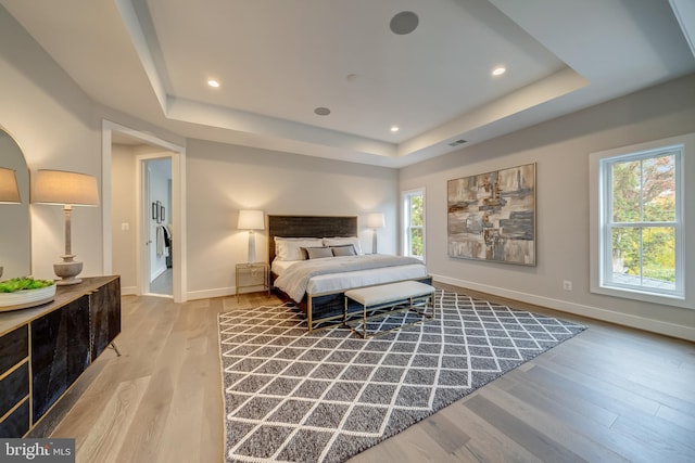 bedroom featuring a raised ceiling and light hardwood / wood-style flooring