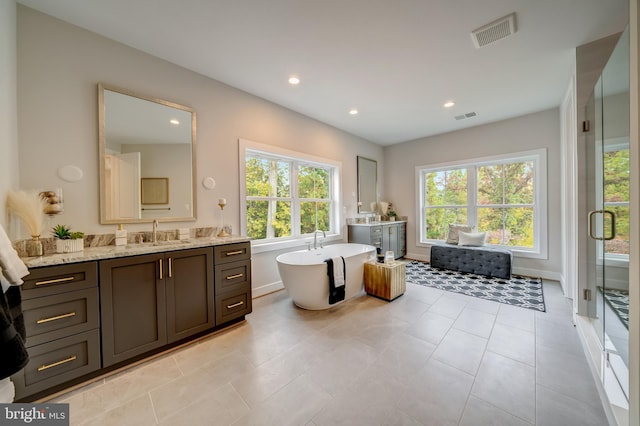 bathroom with a washtub, vanity, and tile floors