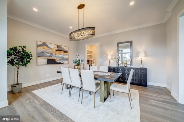 dining room featuring ornamental molding, wood-type flooring, and an inviting chandelier