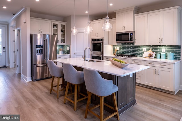 kitchen featuring light hardwood / wood-style floors, tasteful backsplash, stainless steel appliances, sink, and white cabinets