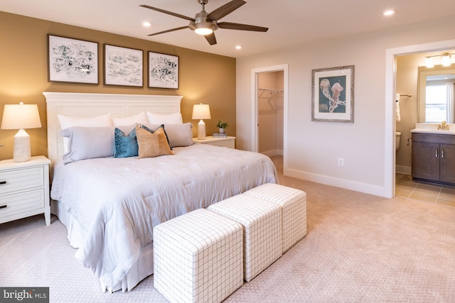 carpeted bedroom featuring connected bathroom, a spacious closet, sink, a closet, and ceiling fan