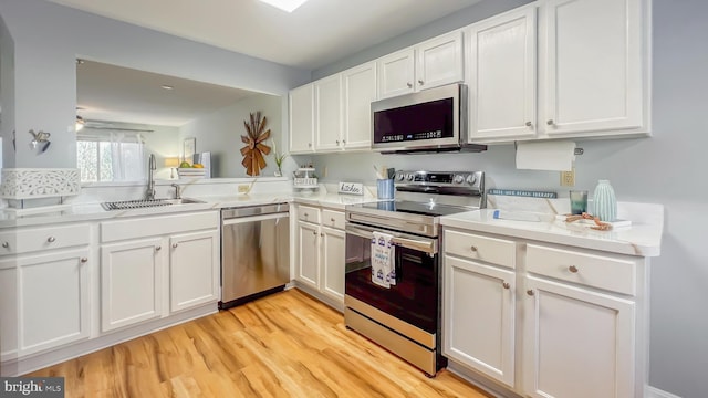 kitchen featuring white cabinetry, appliances with stainless steel finishes, sink, and light wood-type flooring