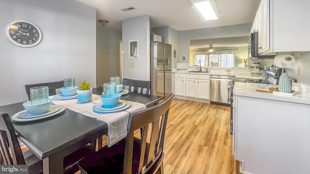 dining area featuring ceiling fan, sink, and light hardwood / wood-style flooring