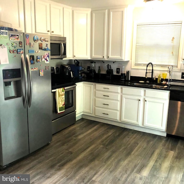 kitchen featuring dark hardwood / wood-style flooring, white cabinetry, sink, and appliances with stainless steel finishes