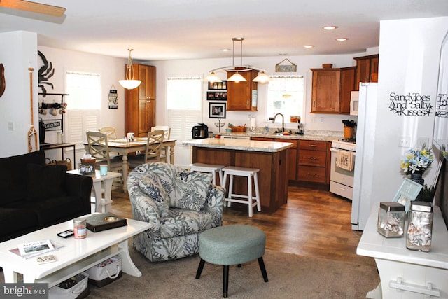 kitchen featuring white gas range, dark hardwood / wood-style flooring, a kitchen island, hanging light fixtures, and sink