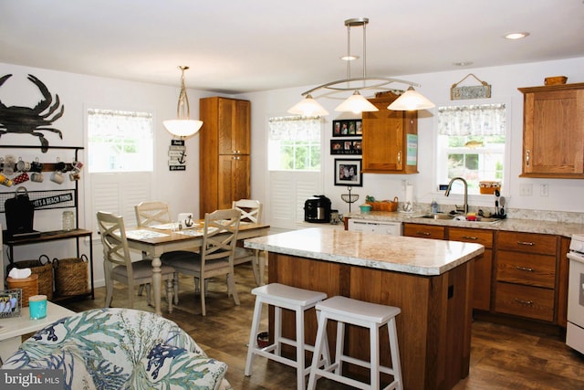 kitchen featuring hanging light fixtures, a center island, a healthy amount of sunlight, and dark hardwood / wood-style flooring