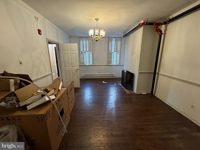 unfurnished dining area with baseboard heating, dark hardwood / wood-style floors, ornamental molding, and an inviting chandelier