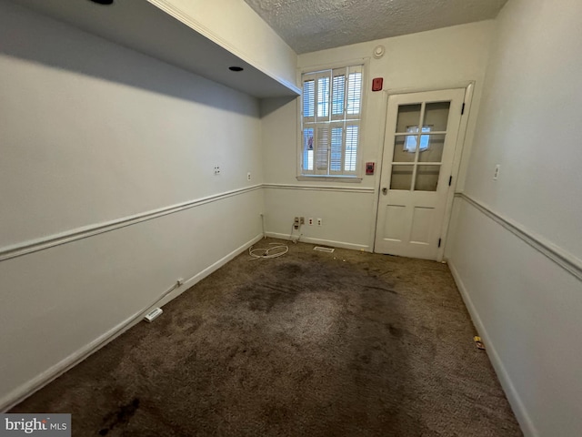 carpeted empty room with a textured ceiling