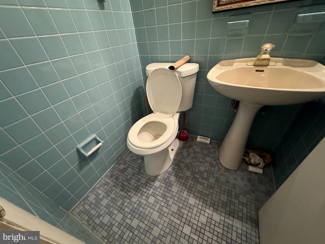 bathroom with toilet, sink, tile walls, and tile patterned floors