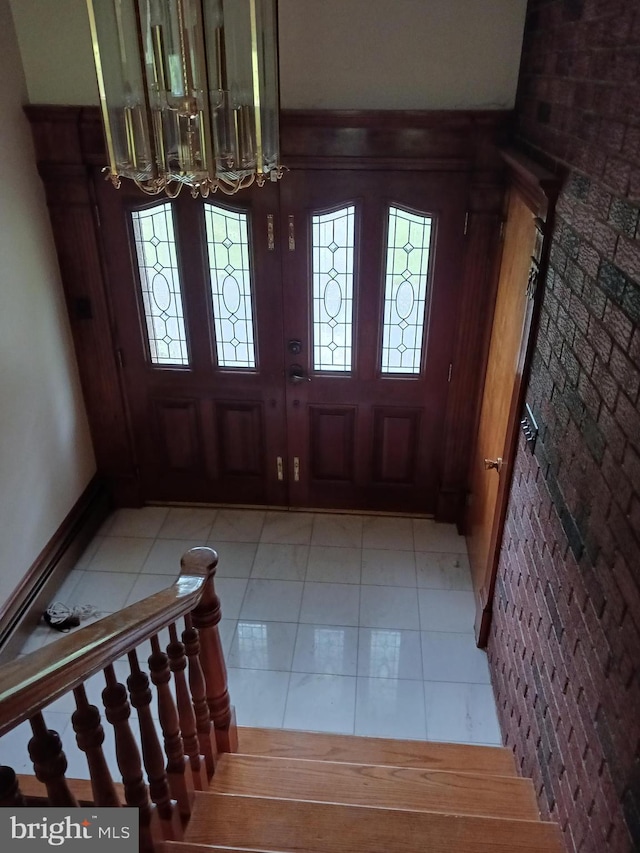 entryway with light tile patterned floors and a notable chandelier