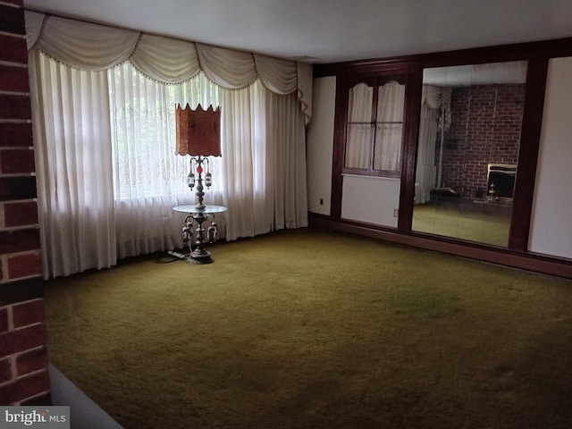 unfurnished room featuring carpet and a brick fireplace