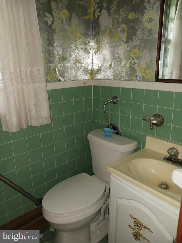 bathroom with vanity, a healthy amount of sunlight, toilet, and tile walls