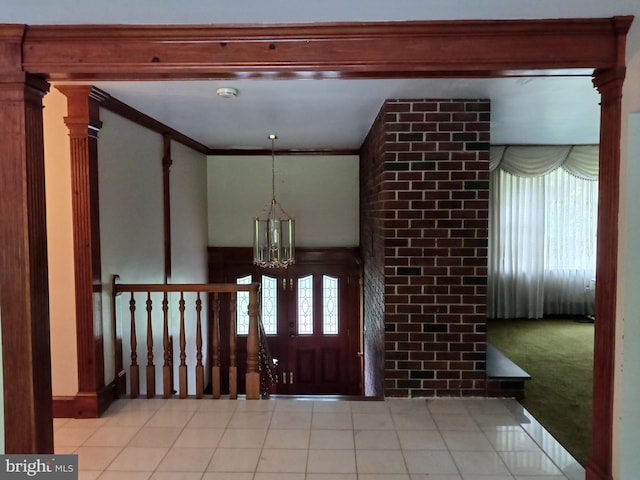 foyer featuring light carpet, ornamental molding, and an inviting chandelier