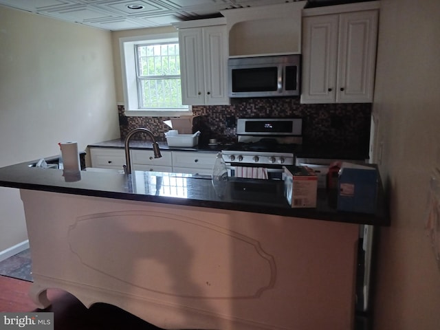 kitchen featuring decorative backsplash, white cabinets, and white stove