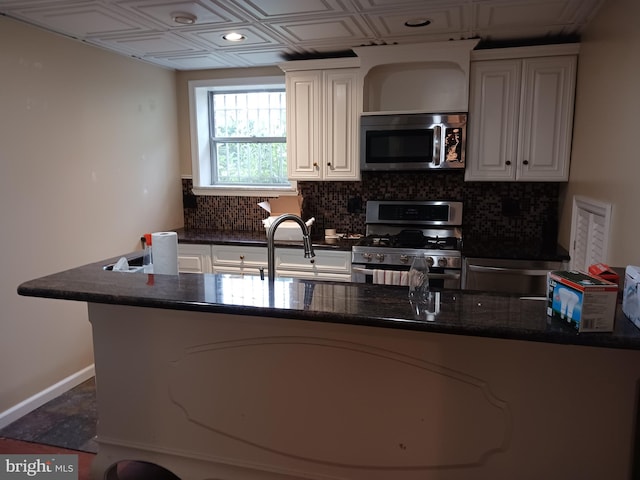 kitchen featuring dark stone counters, decorative backsplash, white cabinetry, and stainless steel appliances