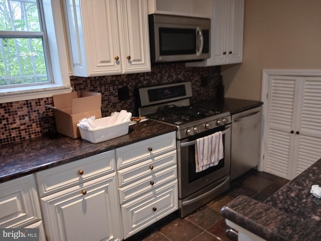 kitchen featuring dark stone counters, white cabinets, dark tile patterned flooring, tasteful backsplash, and stainless steel appliances