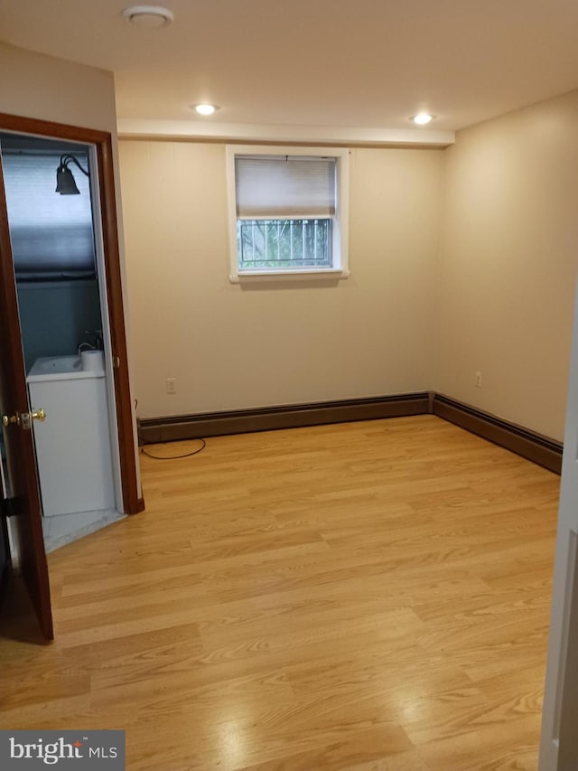 unfurnished room featuring sink, a baseboard radiator, and light hardwood / wood-style flooring