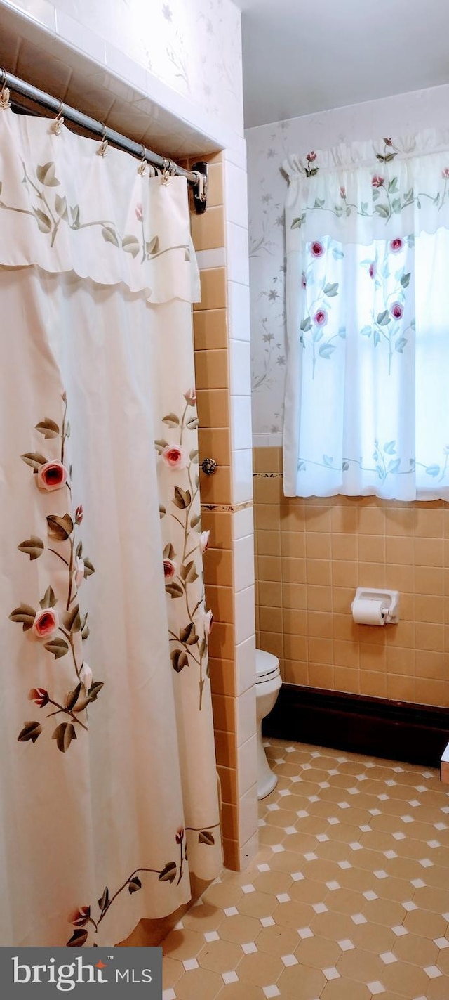 bathroom with toilet and tile walls