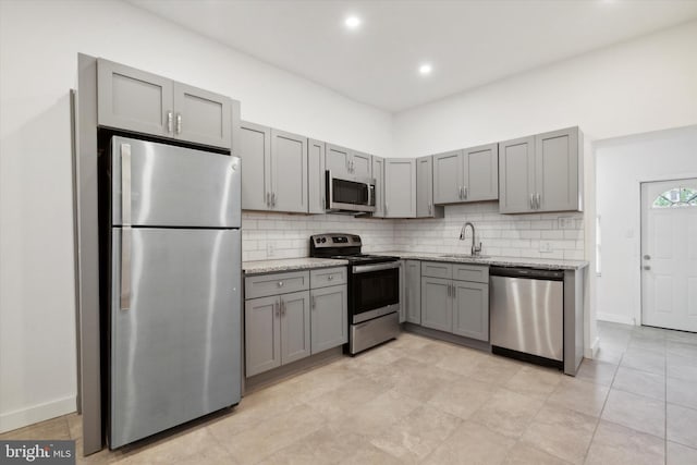 kitchen with stainless steel appliances, backsplash, sink, and light tile floors