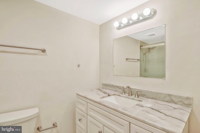 bathroom featuring vanity, toilet, and a shower with shower door