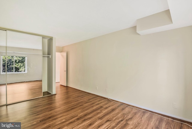 unfurnished bedroom featuring a closet and dark wood-type flooring