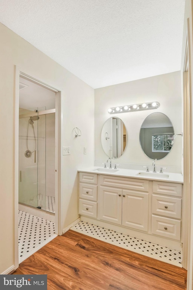 bathroom featuring vanity, a textured ceiling, hardwood / wood-style flooring, and walk in shower