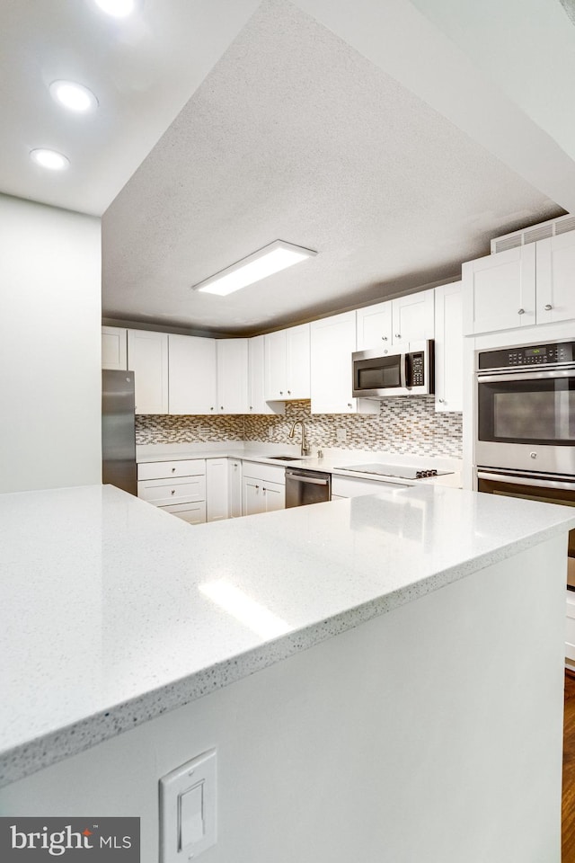 kitchen featuring white cabinets, light stone counters, and appliances with stainless steel finishes