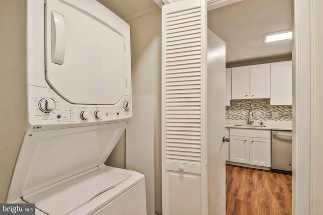 clothes washing area featuring hardwood / wood-style flooring, stacked washer and dryer, and sink