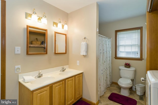 bathroom featuring washer / dryer, dual bowl vanity, tile flooring, and toilet