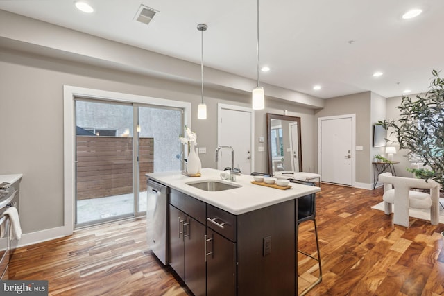 kitchen with dark brown cabinets, sink, hardwood / wood-style flooring, a center island with sink, and dishwasher