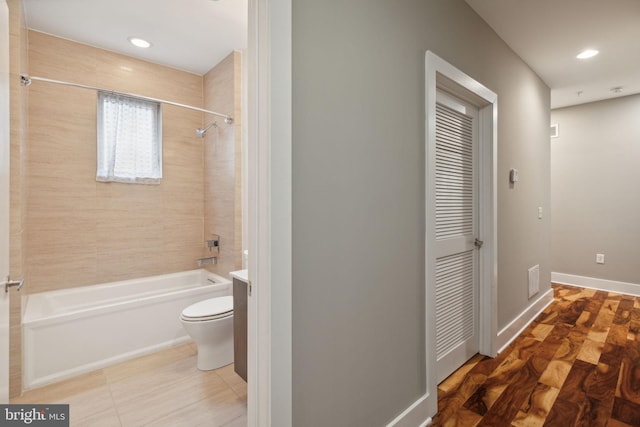 bathroom featuring tile patterned flooring, toilet, and tiled shower / bath