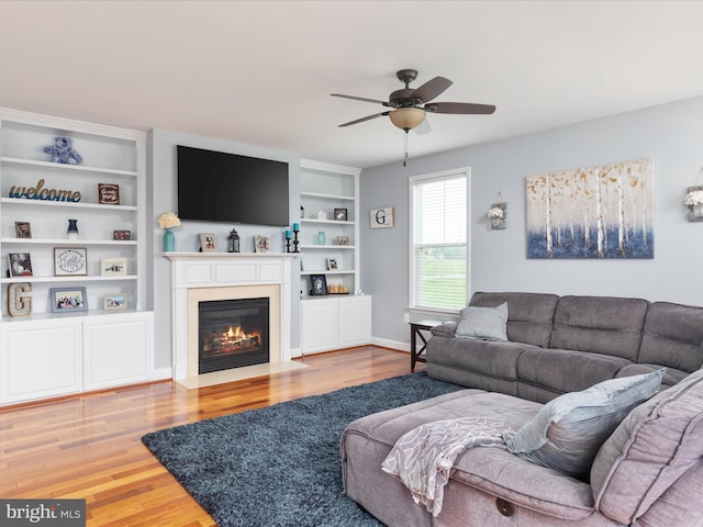 living room with ceiling fan, light hardwood / wood-style floors, and built in shelves