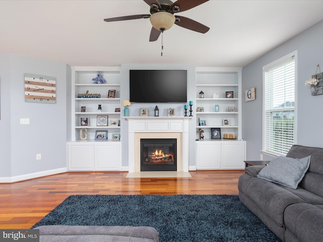 living room featuring ceiling fan, built in shelves, and hardwood / wood-style flooring