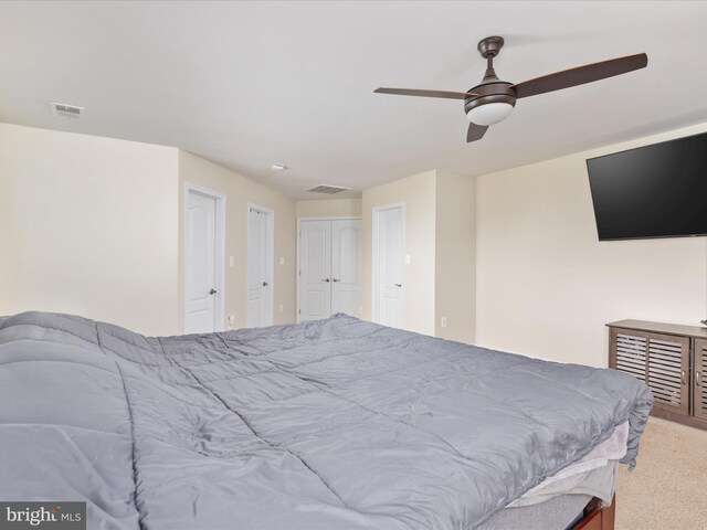 carpeted bedroom featuring ceiling fan and multiple closets