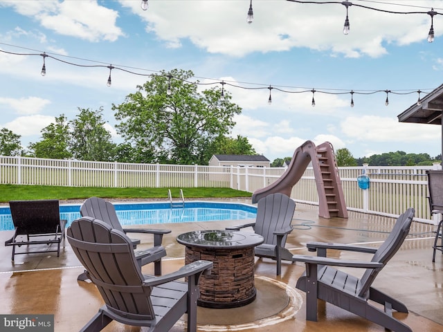 view of pool with a water slide and a patio area