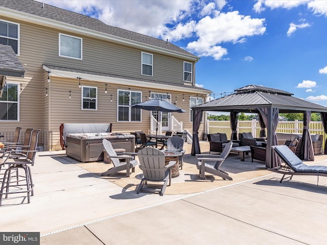 exterior space with a hot tub, a fire pit, a gazebo, and a patio