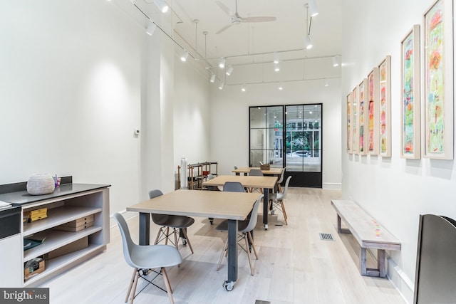 dining space with a high ceiling, ceiling fan, light hardwood / wood-style floors, and track lighting